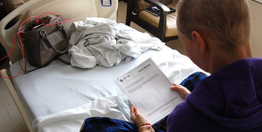 Priscilla Kelly sits in a hospital bed as she reads a Good Wishes note from a friend